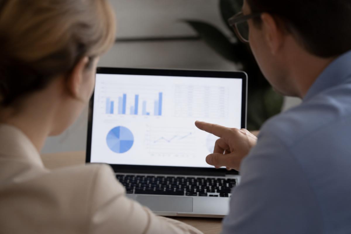 Dois colegas analisando gráficos de desempenho na tela de um notebook