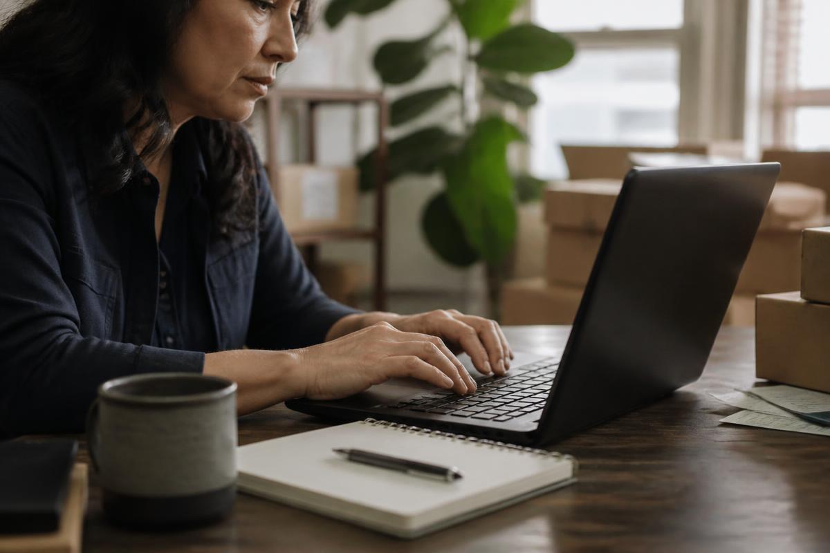 Empreendedora trabalhando em um notebook no estoque do próprio negócio