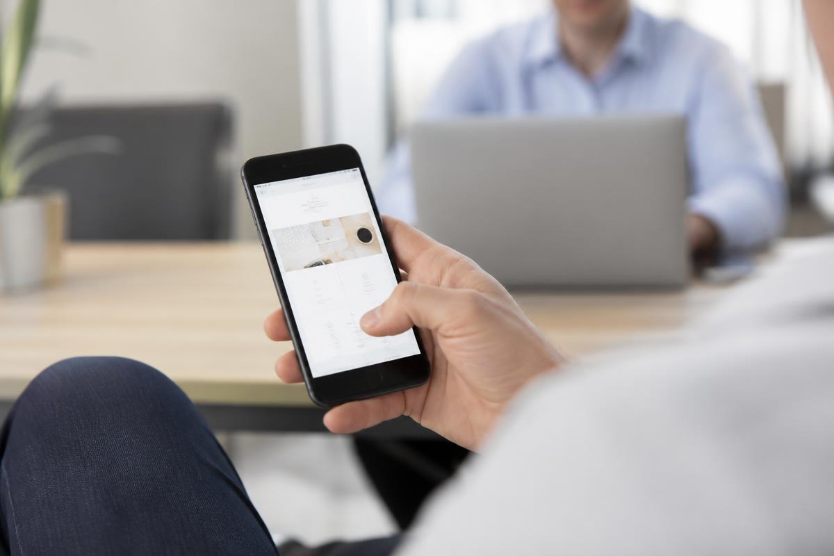 Pessoa navegando pelo site de uma empresa no celular durante uma reunião